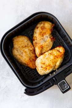 three pieces of chicken sitting in an air fryer on top of a white table