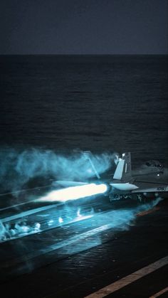 a fighter jet on the deck of an aircraft carrier in the middle of the ocean