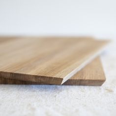 a close up view of a wood flooring board with white carpet in the background