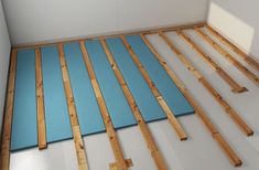 an unfinished room with blue mats on the floor and wooden boards all over the floor