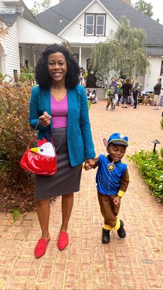 a woman holding the hand of a small boy in front of a house with other people