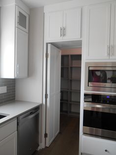 an empty kitchen with white cabinets and stainless steel appliances