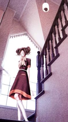 a woman is standing on the stairs with her hair blowing in the wind while wearing a brown dress and white tights