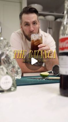 a man sitting at a kitchen counter holding a drink