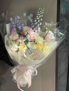 a bouquet of flowers is wrapped in clear cellophane and tied with a ribbon