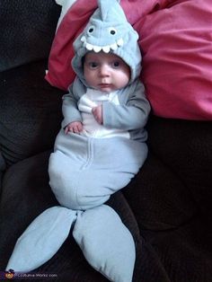 a baby in a shark costume laying on top of a couch