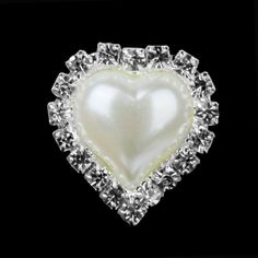 a heart shaped brooch sitting on top of a black surface with diamonds around it