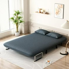 a bed sitting on top of a wooden floor next to a plant in a room