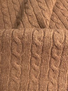 a close up view of a brown sweater with cables on the bottom and sides,