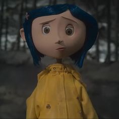 a doll with blue hair wearing a yellow raincoat in front of some trees and snow