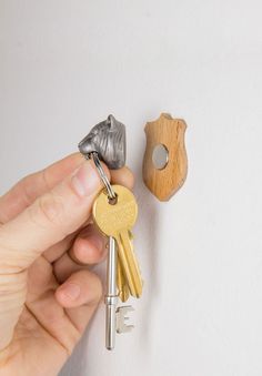 a hand holding keys to a house shaped like a dog and a wooden keychain