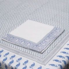 a blue and white table cloth with two napkins on top of it, sitting on a wooden table