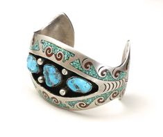 "Vintage large silver with turquoise nugget and coral inlay cuff bracelet -Amazing Navajo artisan handmade cuff -3 large turquoise nuggets surrounded by crushed turquoise and coral inlay in a waves design -Cuff is marked with a pictomark that matches that of artist Charlie Singer, arrowhead mark -Cuff is not marked sterling but acid test shows high silver content - red stain appears with nitric acid test -Cuff is rigid, stamp designs at the ends of the cuff -Very good vintage condition, with pat Southwestern Inlay Cuff Bracelet Gift, Southwestern Turquoise Cuff Bracelet With Inlay, Southwestern Style Turquoise Cuff Bracelet With Inlay, Waves Design, Red Stain, Turquoise And Coral, Turquoise Cuff, Vintage Navajo, Wave Design