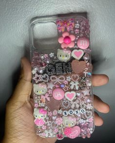 someone is holding their cell phone case with hello kitty and other items on the back