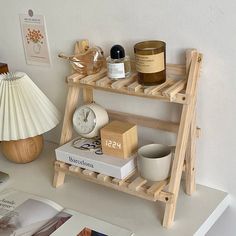 a wooden shelf with books, candles and other items on it next to a lamp