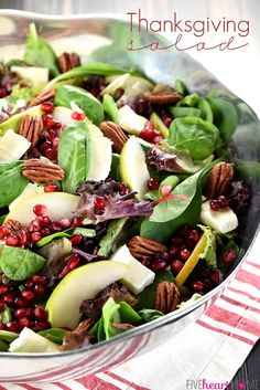 a white plate topped with spinach, cheese and pomegranate on top of lettuce