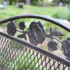 an iron bench with flowers on it in a park