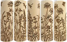 four wooden vases with flowers and plants etched on them, lined up against a white background