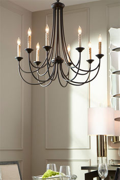 a chandelier hanging over a dining room table with wine glasses on the table