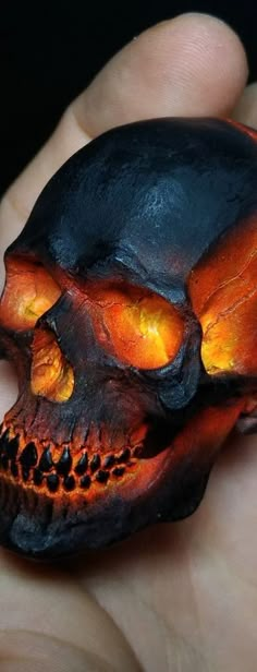 a hand holding a fake skull in it's left hand, with orange light coming from its eyes