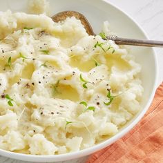 a white bowl filled with mashed potatoes and garnished with green sprigs