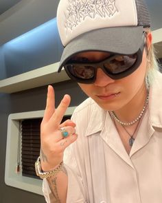 a person wearing a hat and sunglasses making the peace sign