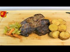 a wooden cutting board topped with meat, potatoes and carrots