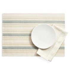 a plate and napkin on top of a striped placemat with a white bowl in the middle