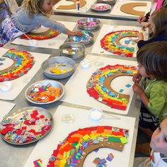 children are making crafts at a table with paper plates