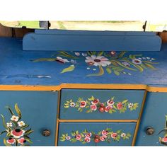 an old blue painted dresser with flowers on it