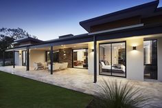 a modern house is lit up at night with lights on the windows and patio area