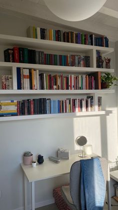 a white desk topped with a laptop computer next to a book shelf filled with books