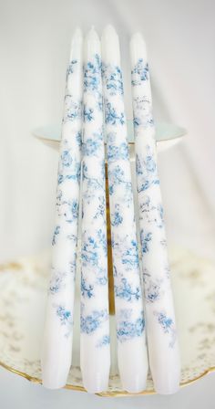 four white and blue candles sitting on top of a cake plate next to each other