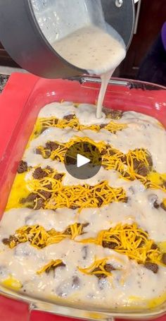 someone is pouring sauce on a casserole dish with cheese and other toppings