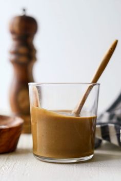 a glass cup filled with liquid next to a wooden spoon