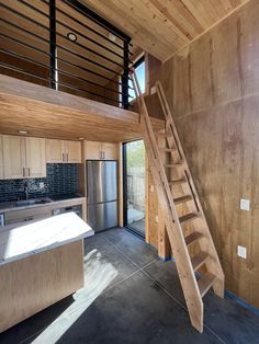 a kitchen with wooden walls and stairs leading to the upper floor