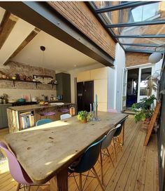 a wooden table sitting on top of a wooden floor next to a kitchen and dining room