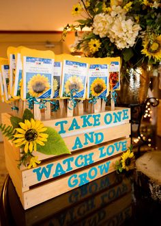 sunflowers are placed on top of a wooden sign that says take one and watch love grow