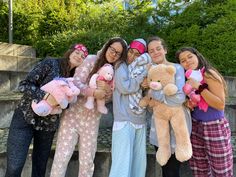 four girls are holding stuffed animals and posing for the camera