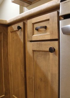 the kitchen cabinets are made of wood and have black knobs on them, along with a stainless steel dishwasher