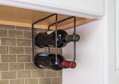 three bottles of wine are hanging on the wall in front of a tile backsplash