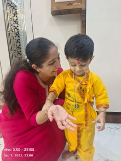 a woman is showing a small boy how to put his hand on him's finger