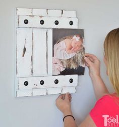 a woman is holding up an old shutter frame with a baby's photo on it