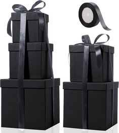 two black boxes are stacked up with ribbons on them and one has a light in the middle