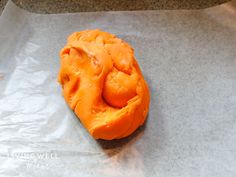 an orange doughnut sitting on top of a piece of wax paper