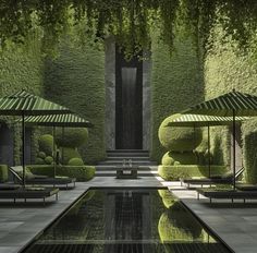 an outdoor pool surrounded by green plants and umbrellas with water running through the center