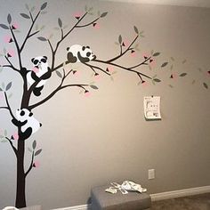 a baby's room with a panda bear mural on the wall and tree decals