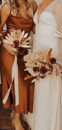 two women standing next to each other in dresses and holding bouquets with flowers on them