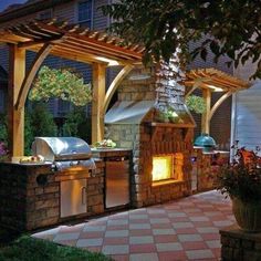 an outdoor kitchen is lit up at night with the lights on and grill in the background