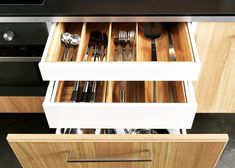 an open drawer with utensils and silverware in it on a counter top